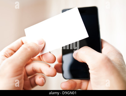 Uomo con blank business card e comporre i numeri sul telefono cellulare Foto Stock