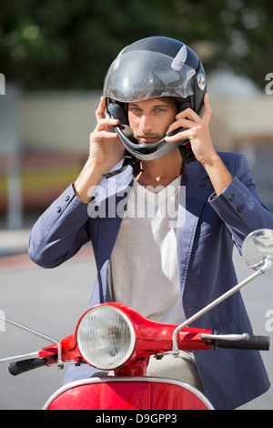 Uomo seduto su uno scooter e indossa un casco Foto stock - Alamy