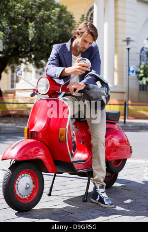 Uomo seduto su uno scooter e indossa un casco Foto stock - Alamy