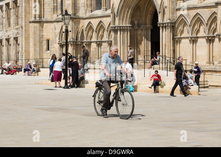 Ciclista passando York Minster sulla nuova pavimentazione (2013) al di fuori del transetto sud Foto Stock