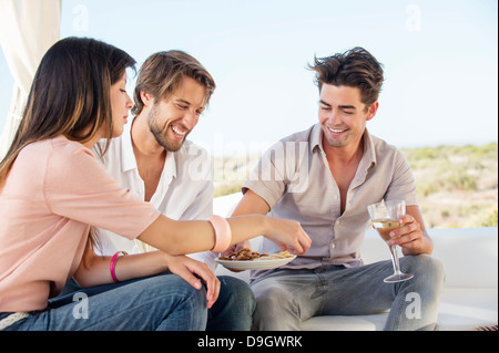 Tre amici godersi spuntini e bevande in esterni Foto Stock
