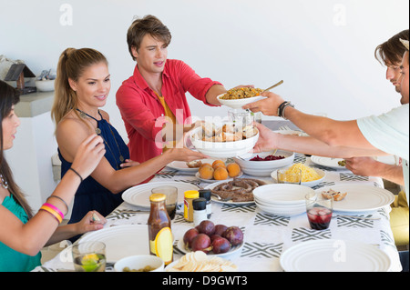Amici che passano il cibo bocce al tavolo da pranzo Foto Stock