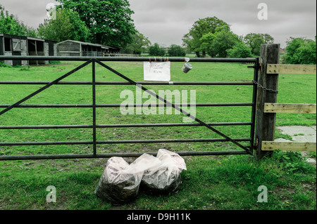 Due sacchetti di letame equino in vendita nella parte anteriore di una azienda agricola nelle zone rurali Yorkshire. Le monete sono sceso nella casella di onestà. Foto Stock