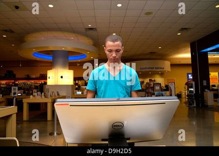 Un giovane uomo guarda al computer in un campus bookstore. Foto Stock