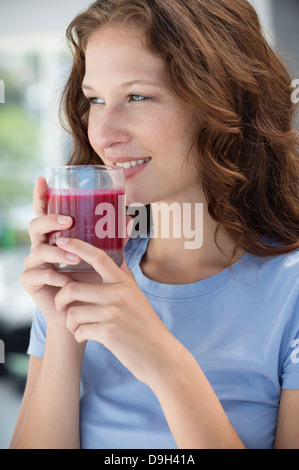 Donna sorridente con in mano un bicchiere di succo di melograno Foto Stock