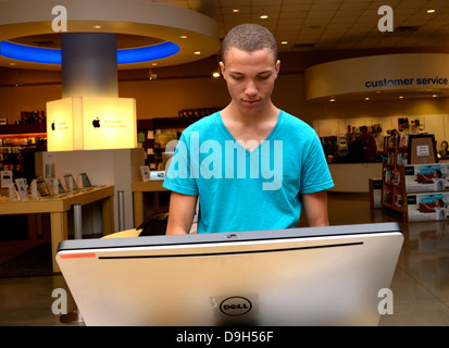 Un giovane uomo guarda al computer in un campus bookstore. Foto Stock