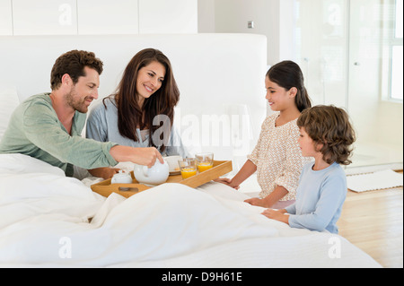 I bambini che serve tè ai loro genitori sul letto Foto Stock
