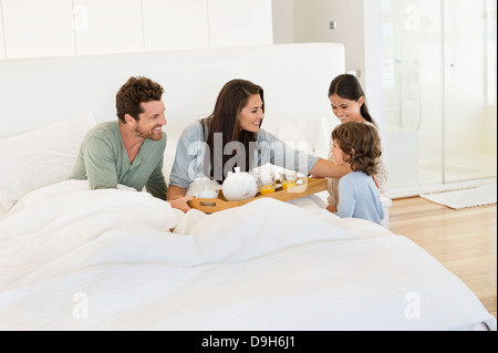 I bambini che serve tè ai loro genitori sul letto Foto Stock