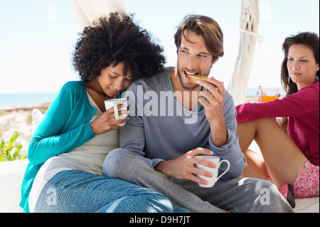 Giovane avente il caffè con il loro amico in background Foto Stock