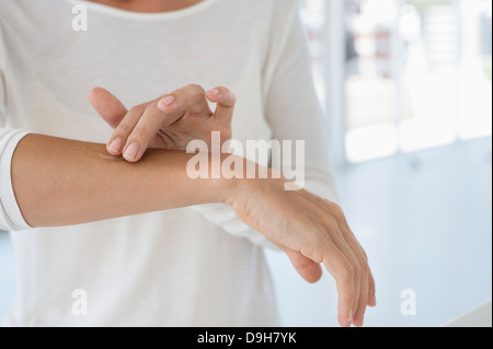 Donna applicazione di unguento sulla sua mano Foto Stock