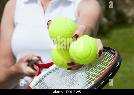 Palle da tennis in mano a un giocatore sopra le corde della racchetta Foto Stock