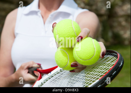 Palle da tennis in mano a un giocatore sopra le corde della racchetta Foto Stock