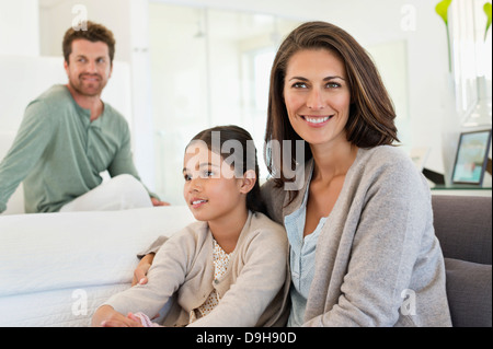 Donna seduta con sua figlia e suo marito in background Foto Stock
