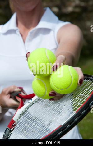 Palle da tennis in mano a un giocatore sopra le corde della racchetta Foto Stock