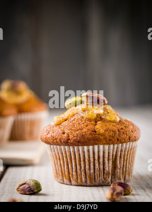 Grano intero muffin alla carota con glassa arancione e pistacchi. Foto Stock