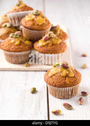 Grano intero muffin alla carota con glassa arancione e pistacchi. Foto Stock