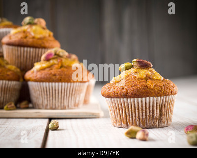 Grano intero muffin alla carota con glassa arancione e pistacchi. Foto Stock