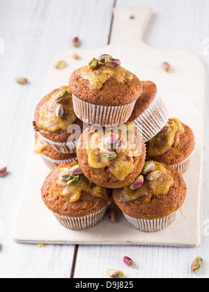 Grano intero muffin alla carota con glassa arancione e pistacchi. Foto Stock