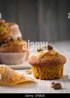 Grano intero muffin alla carota con glassa arancione e pistacchi. Foto Stock