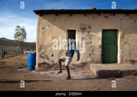 Giovane ragazzo in pratica la sua abilità calcistiche utilizzando uno strumento realizzato localmente pallone da calcio in rural Transkei, Sud Africa Foto Stock