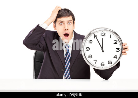 Scioccato l uomo in un vestito, seduto e in possesso di un orologio Foto Stock