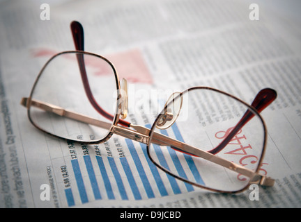 Occhiali su un giornale con la tabella finanziaria Foto Stock