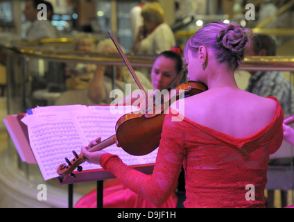 Signora violinisti giocare. Profondo rosso abiti e moody magenta evidenziazione su argomenti. Foto Stock