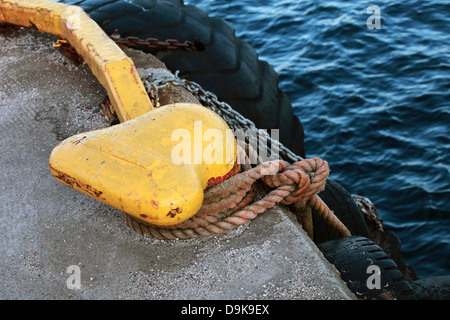 Giallo bollard ormeggio con blu corda navale e la catena sul molo Foto Stock