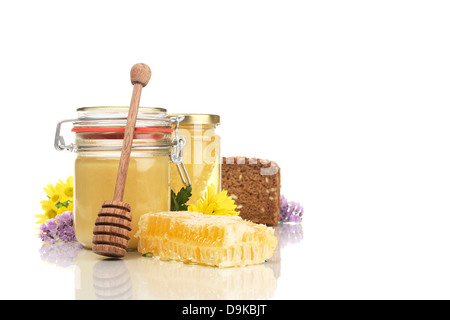 Occhiali di miele di favo di miele, pane integrale, cucchiaio di miele e fiori, vasetti favo di miele, pane integrale, miele e fl Foto Stock