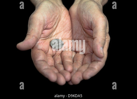 La povertà. Vecchie mani con una singola moneta da 25 centesimi Foto Stock