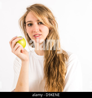 Un sano giovane donna con capelli lunghi biondi tenendo una mela verde Foto Stock