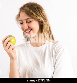 Un sano giovane donna con capelli lunghi biondi tenendo una mela verde - mangiare frutta fresca Foto Stock