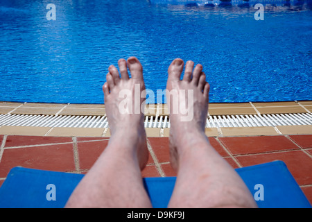 Mans dei piedi e delle gambe dal lato di una piscina in vacanza Salou Costa Dorada Spagna Foto Stock
