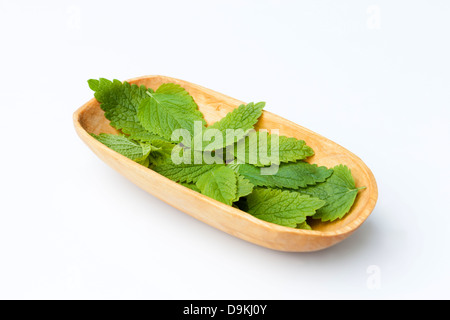 Melissa (Melissa officinalis) lascia il raccolto in una ciotola di legno Foto Stock