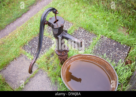 Vecchio bagnato in ghisa pompa acqua in giardino Foto Stock