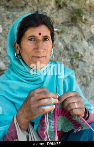 Un Gaddi tribeswoman maglieria un indumento mentre posa per la fotocamera al villaggio himalayana di Kugti in Himachal Pradesh, India Foto Stock