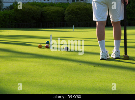 Un gioco di golf croquet. Un giocatore guarda come un altro giocatore si avvicina a sfera il paletto. Foto Stock