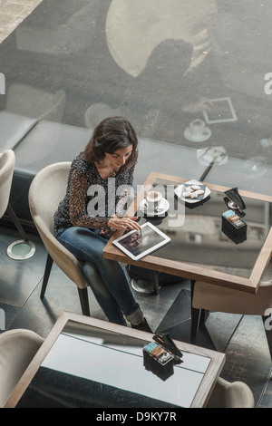 Donna che utilizza digitale compressa in cafe Foto Stock