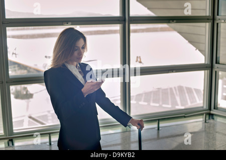 Giovane donna utilizza lo smartphone in aeroporto Foto Stock