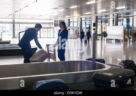 Gli imprenditori in aeroporto presso il reclamo bagagli Foto Stock