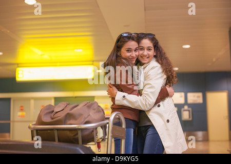 Due ragazze adolescenti abbracciando in aeroporto Foto Stock