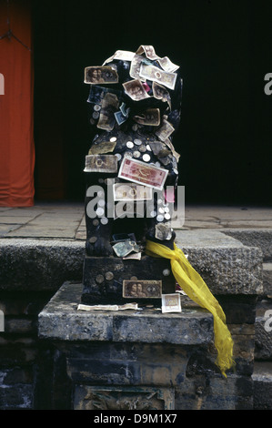 Yuan Renminbi di banconote e monete attaccato ad una statua in tibetano Kumbum gompa monastero chiamato anche Ta'er tempio fondata nel 1583 in una valle stretta vicino al villaggio di Lusar nella storica regione tibetana di Amdo nella contea di Huangzhong, in Xining la capitale della Provincia di Qinghai in Cina occidentale Foto Stock