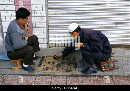 Uomini cinesi che giocano Xiangqi anche chiamato scacchi cinesi che è un gioco di strategia da tavolo in un marciapiede nella città di Tongren nella provincia di Guizhou Cina Foto Stock