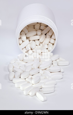 Compresse fuoriuscita dal contenitore - vitamina pillole fuoriuscita da un contenitore in plastica. Foto Stock