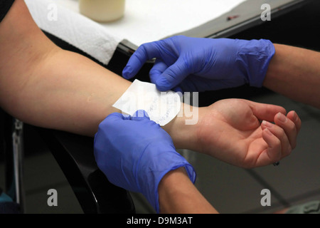 Persona che viene preparata con stencil a farsi un tatuaggio sul polso sinistro, artista indossando guanti blu Foto Stock