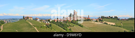 Panorama di piccole tipica città italiana con il castello medievale, hill, vigneti e montagne sullo sfondo in Piemonte, Italia. Foto Stock