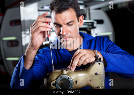 Meccanico specializzato riparazione macchina per cucire industriale in fabbrica Foto Stock