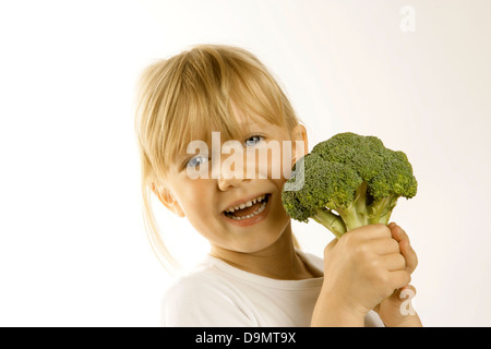 Giovane ragazza con un grande capo di broccoli. La promozione di mangiare le verdure come parte di un helathy dieta bilanciata Foto Stock