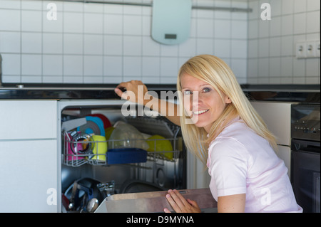 (Modello di rilascio) donna lavora in cucina con una rondella Foto Stock