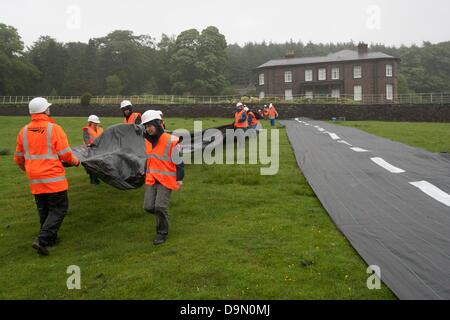 20 attivisti vestito in roadbuilders' alta viz capi di abbigliamento e copricapi rigidi roll out di un fake road nel campo immediatamente al di sotto della Rupe Hall, Cheshire in chi sta sostenendo il Cancelliere dello scacchiere George Osbornes ha una residenza . La protesta è stata fatta per evidenziare l'atteso rilascio di denaro per regimi roadbuilding in tutto il Regno Unito nella spesa imminente esaminare mercoledì 26 giugno Foto Stock